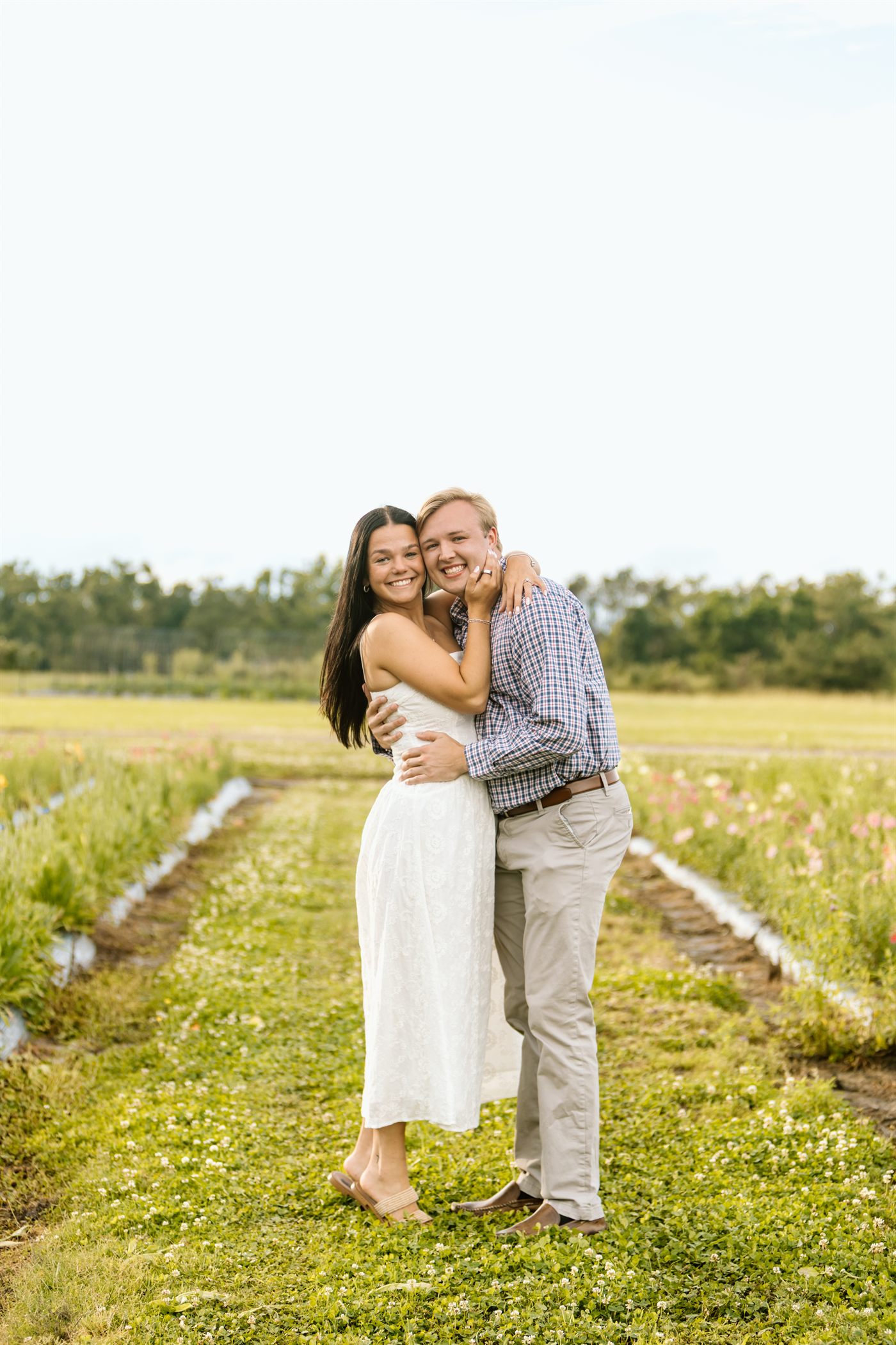 Maria and Bailey embracing in a sunlit flower field